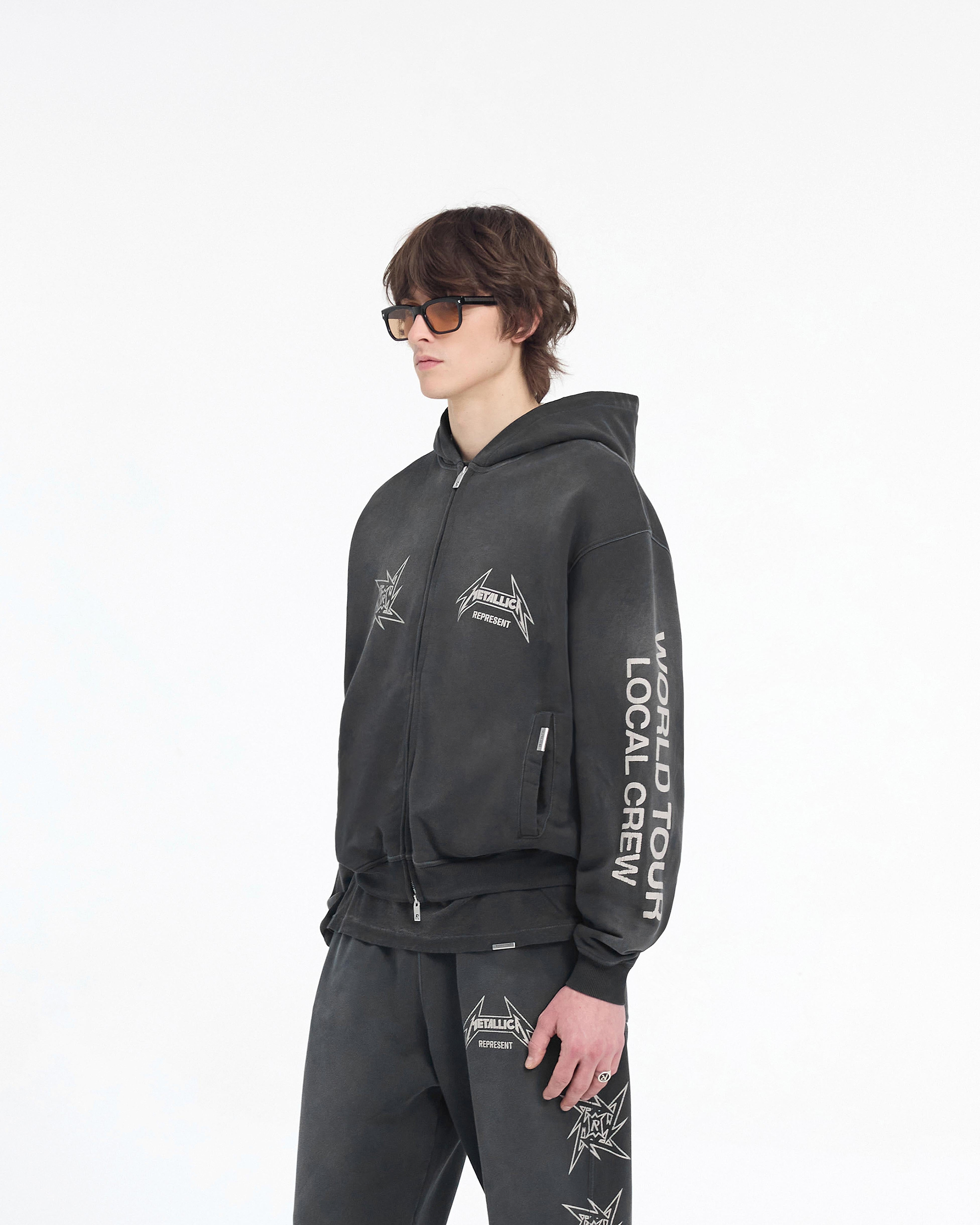 Man wearing a black hoodie on a plain white background | Represent X Metallica Local Crew Zip Hoodie in Stained Black | Oversized hoodie with cracked graphics and RiRi zip | SS24 Hoodies | Represent Clo