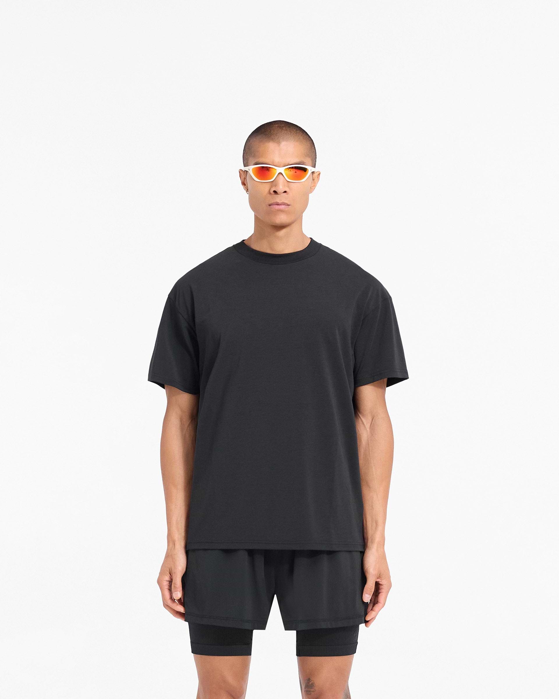 Man wearing a black oversized t-shirt on a plain white background | 247 DNA Oversized T-Shirt in Black | Quick drying lightweight t-shirt with 4-way stretch | 247 T-Shirts | Represent Clo