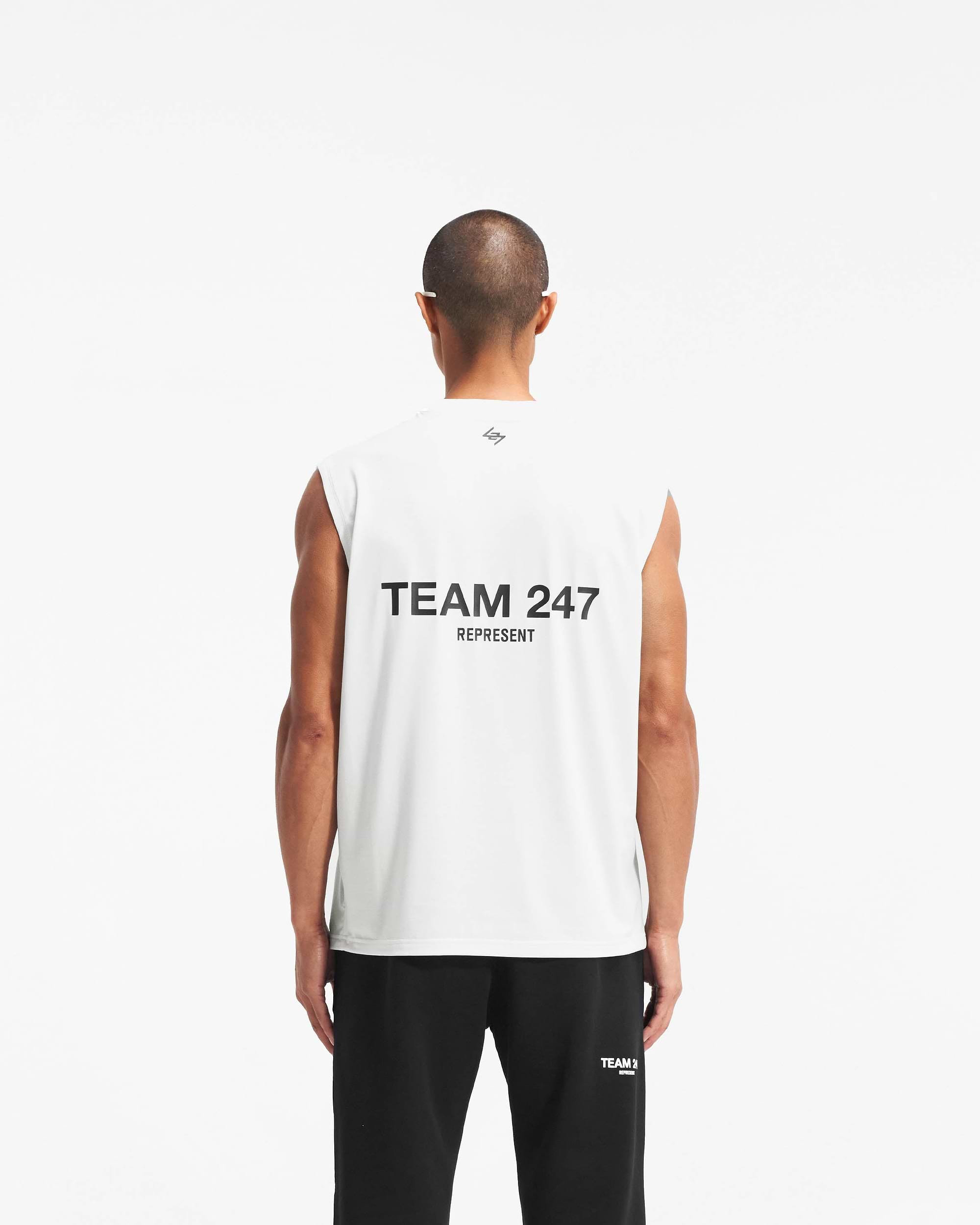 Man wearing a white oversized tank on a plain white background | Team 247 Oversized Tank in Flat White | Oversized tank with 4-way stretch and Team 247 branding | 247 T-Shirts | Represent Clo