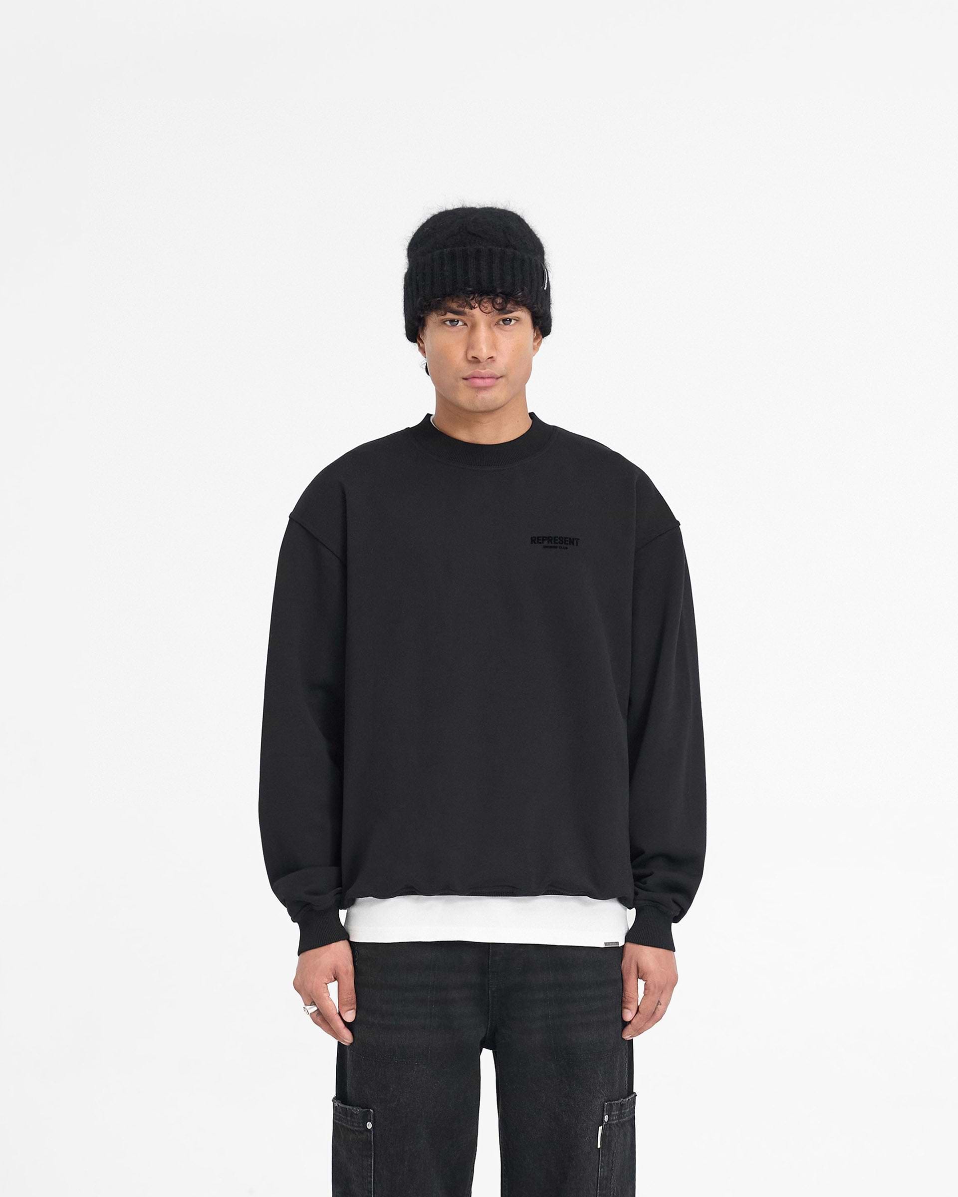 Man wearing a black sweater on a plain white background | Represent Owners Club Flocked Sweater in Black | Oversized sweater with ribbed trims and flocking print | Owners Club Sweaters | Represent Clo
