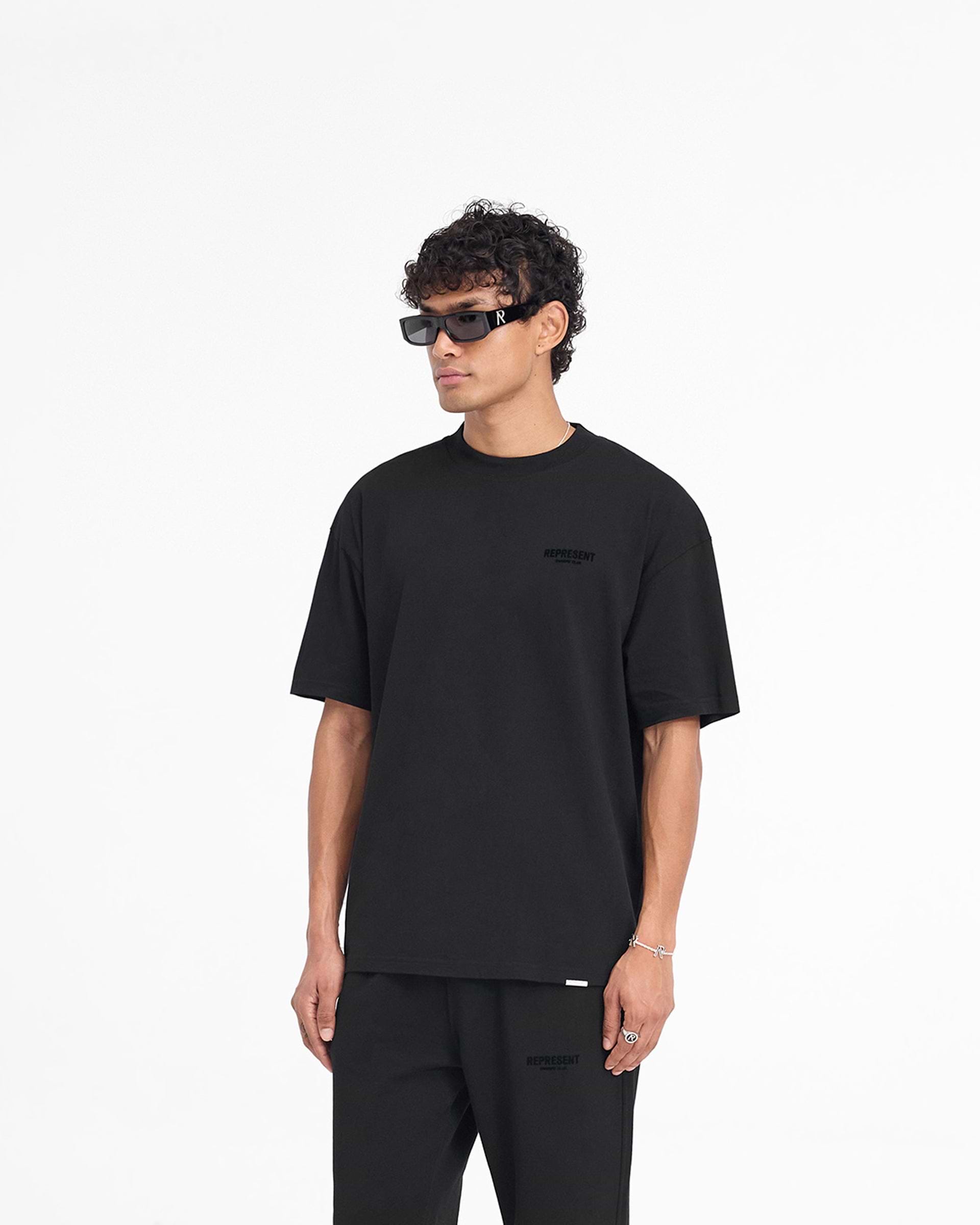 Man wearing a black t-shirt on a plain white background | Represent Owners Club Flocked T-Shirt in Black | Oversized short sleeve t-shirt with flocking print | Owners Club T-Shirts | Represent Clo