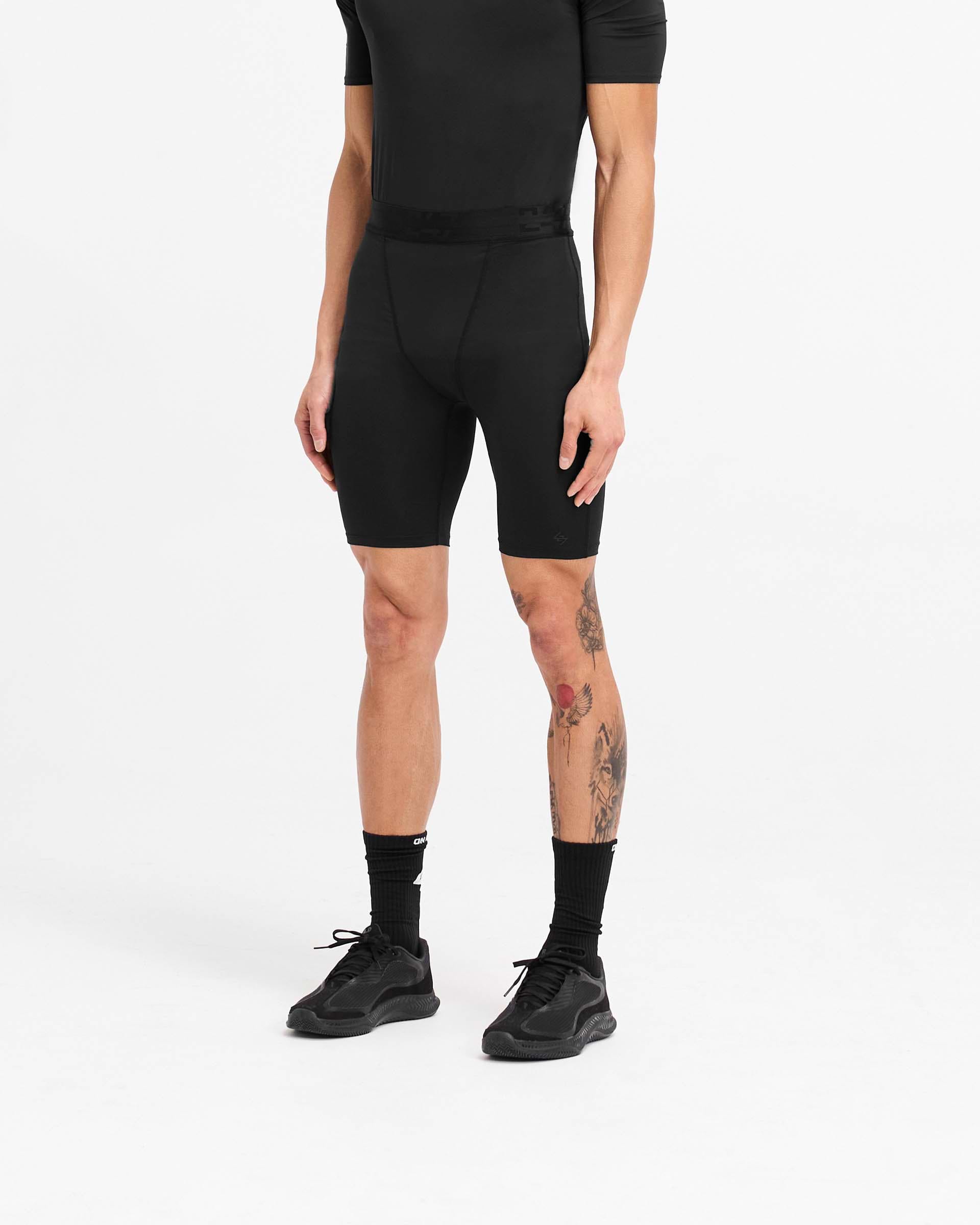 Man wearing black legging shorts on a plain white background | 247 Compound Legging Short in Black | Performance shorts with elasticated waistband and fused pocket | 247 Shorts | Represent Clo