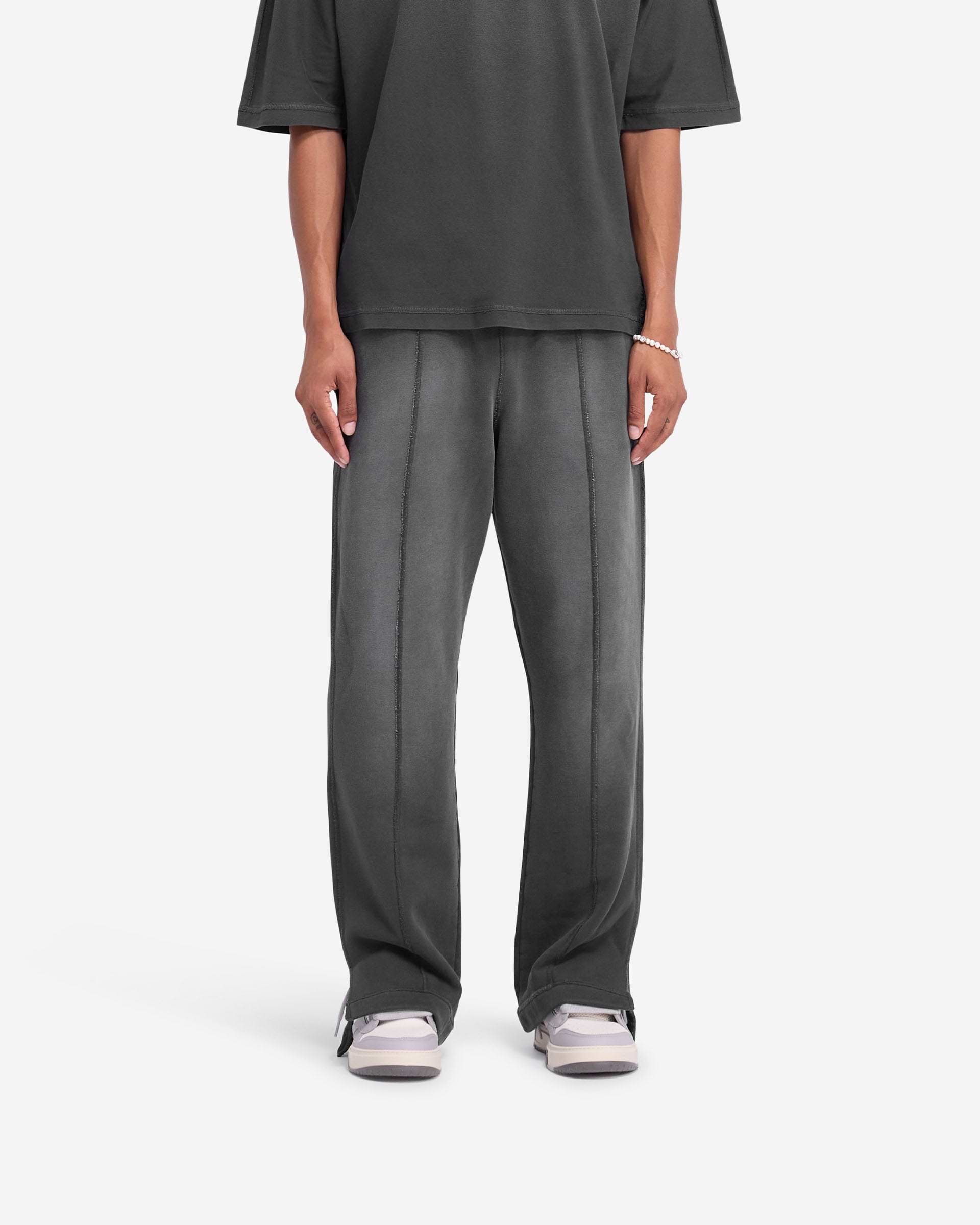 Man wearing wide leg black sweatpants on a plain white background | Stepped Hem Sweatpants in Stained Black | Sweatpants with stepped hem and fade out wash | FW24 Pants | Represent Clo