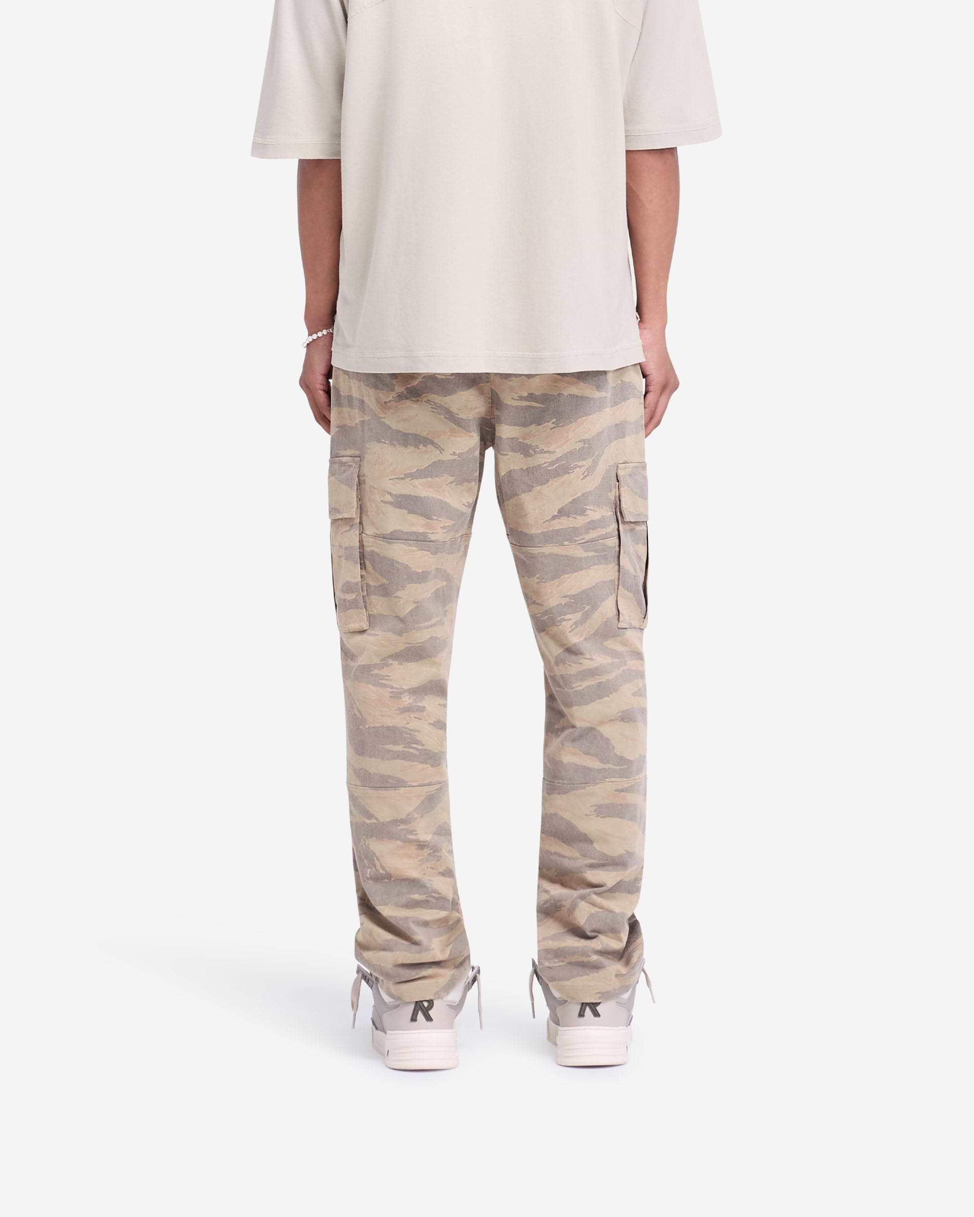 Man wearing camo pants on a plain white background | Cargo Pant in Camo | Regular fit camo pants with elasticated waistband and flap pockets | FW24 Pants | Represent Clo