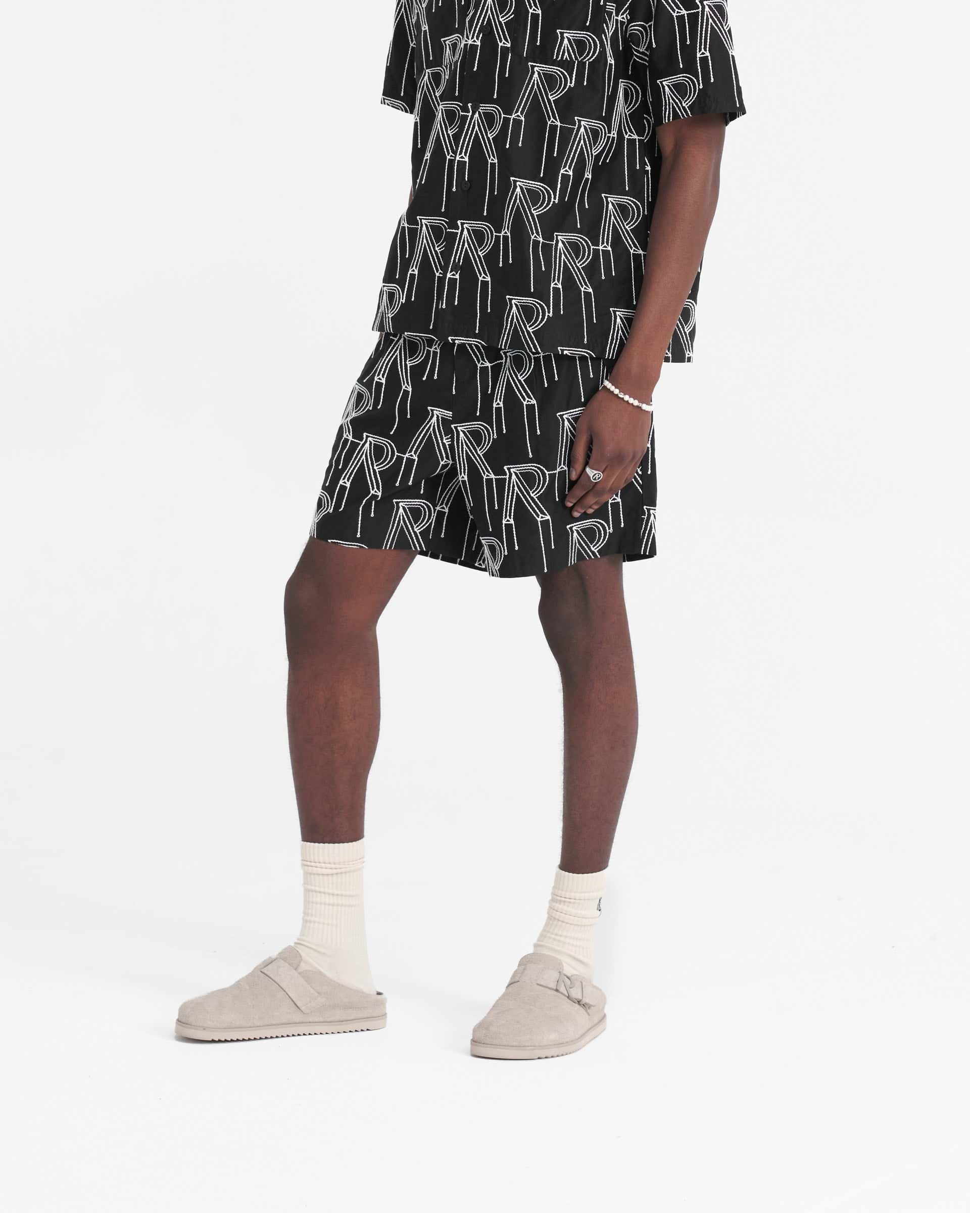 Back product image of mens black tailored shorts on a plain white background | Embroidered Initial Tailored Short in Black | Tailored shorts with raised chain stitch embroidery and pleats | SS24 Shorts | Represent Clo
