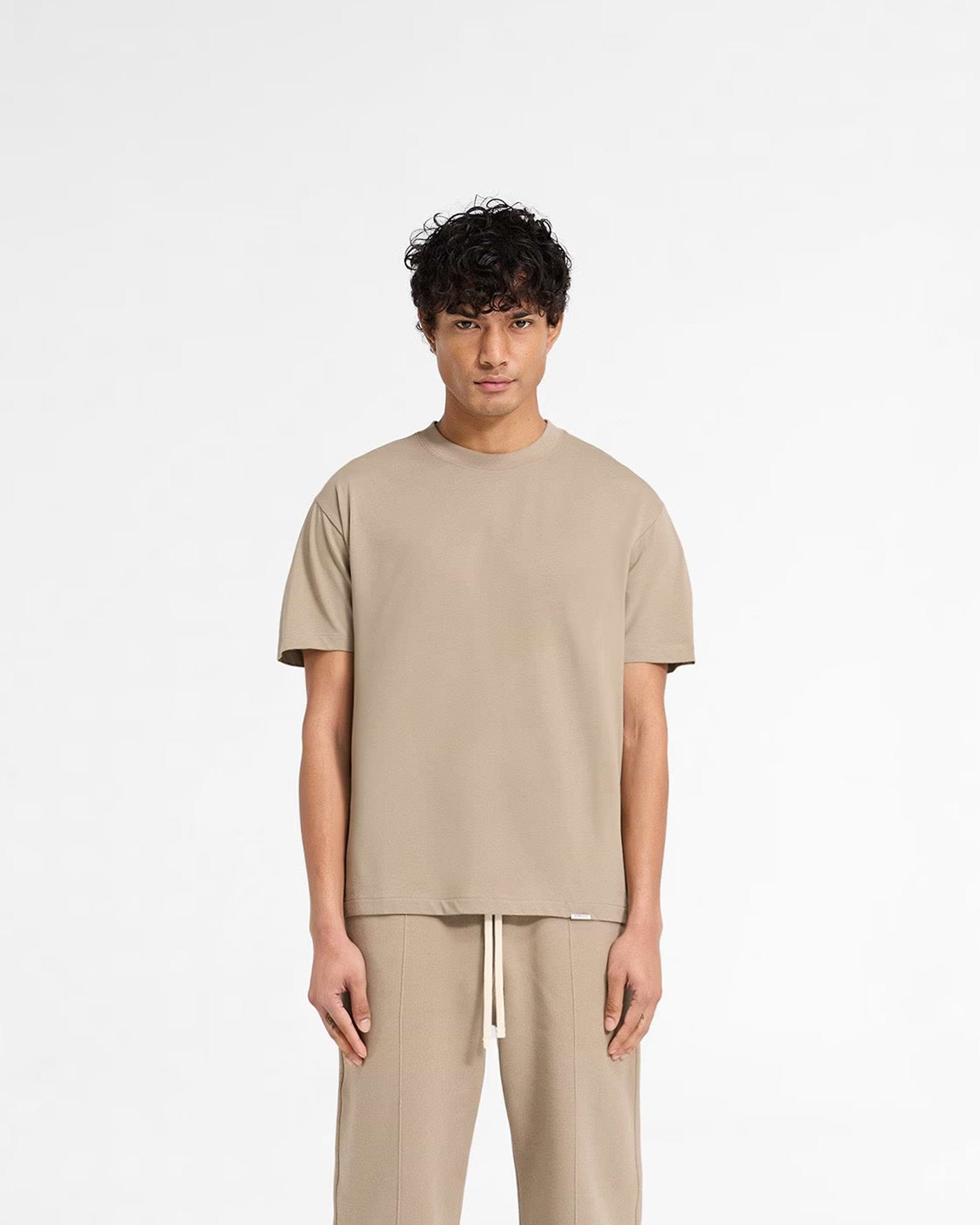 Man wearing a dune t-shirt on a plain white background | Initial T-Shirt in Dune | Fitted tee with embroidered back neck detail | Initial T-Shirts | Represent Clo