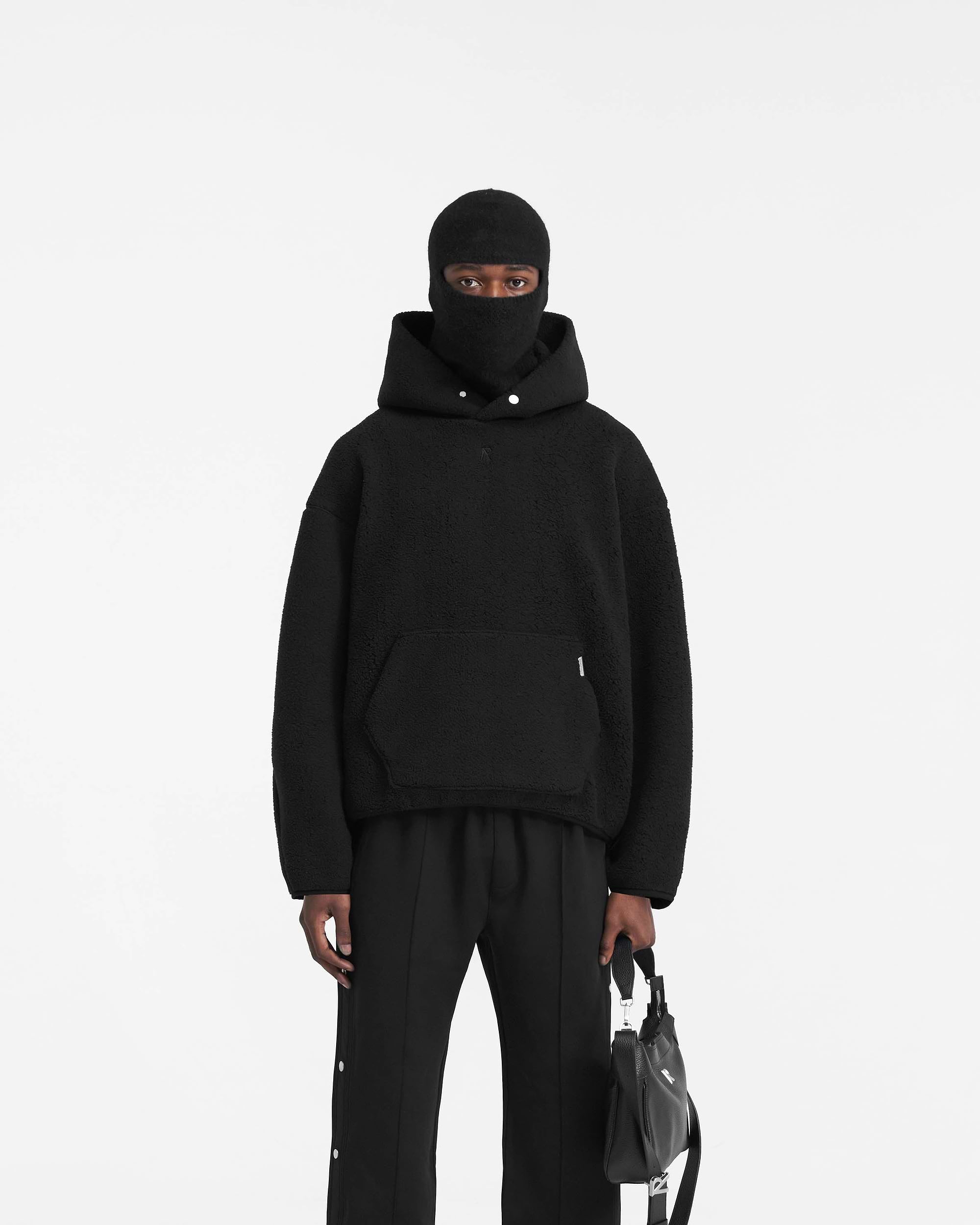 Man wearing an oversized black hoodie on a plain white background | Fleece Oversized Hoodie in Black | Extra oversized hoodie with embroidered Initial logo | PRE SS24 Hoodies | Represent Clo