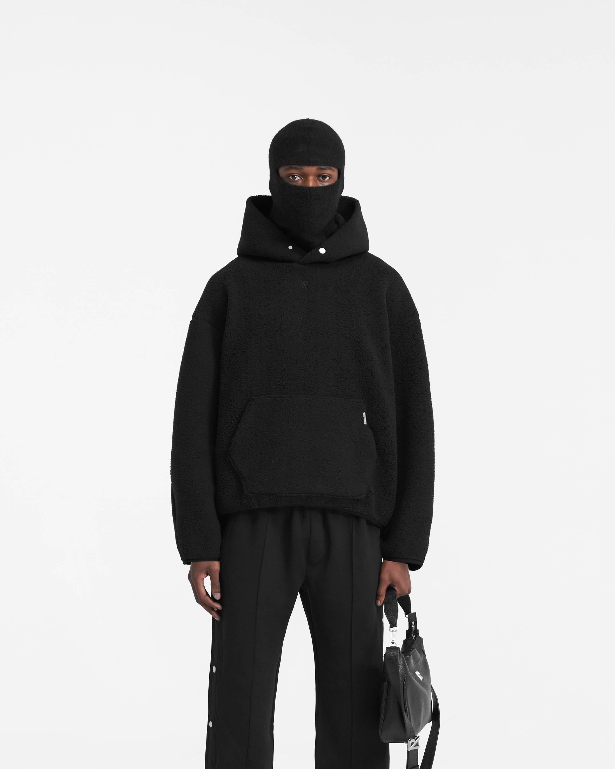 Man wearing an oversized black hoodie on a plain white background | Fleece Oversized Hoodie in Black | Extra oversized hoodie with embroidered Initial logo | PRE SS24 Hoodies | Represent Clo