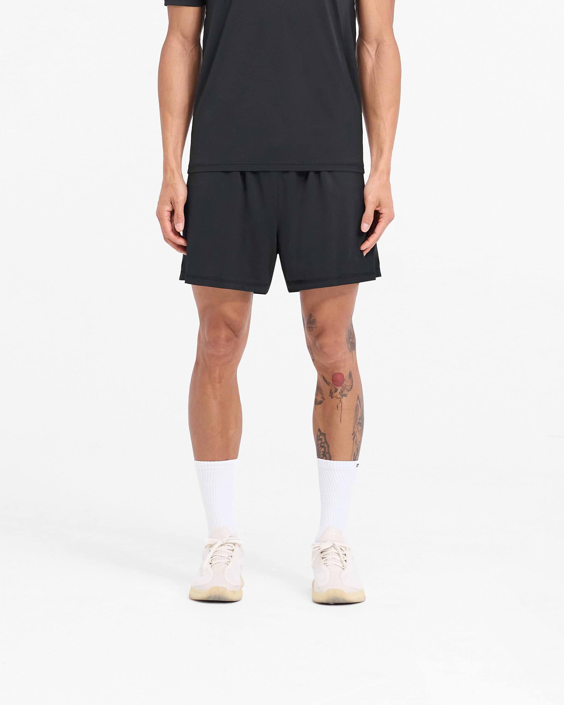 Man wearing black mesh shorts on a plain white background | 247 DNA Mesh Shorts in Black | Oversized shorts with side zip pockets | 247 Shorts | Represent Clo