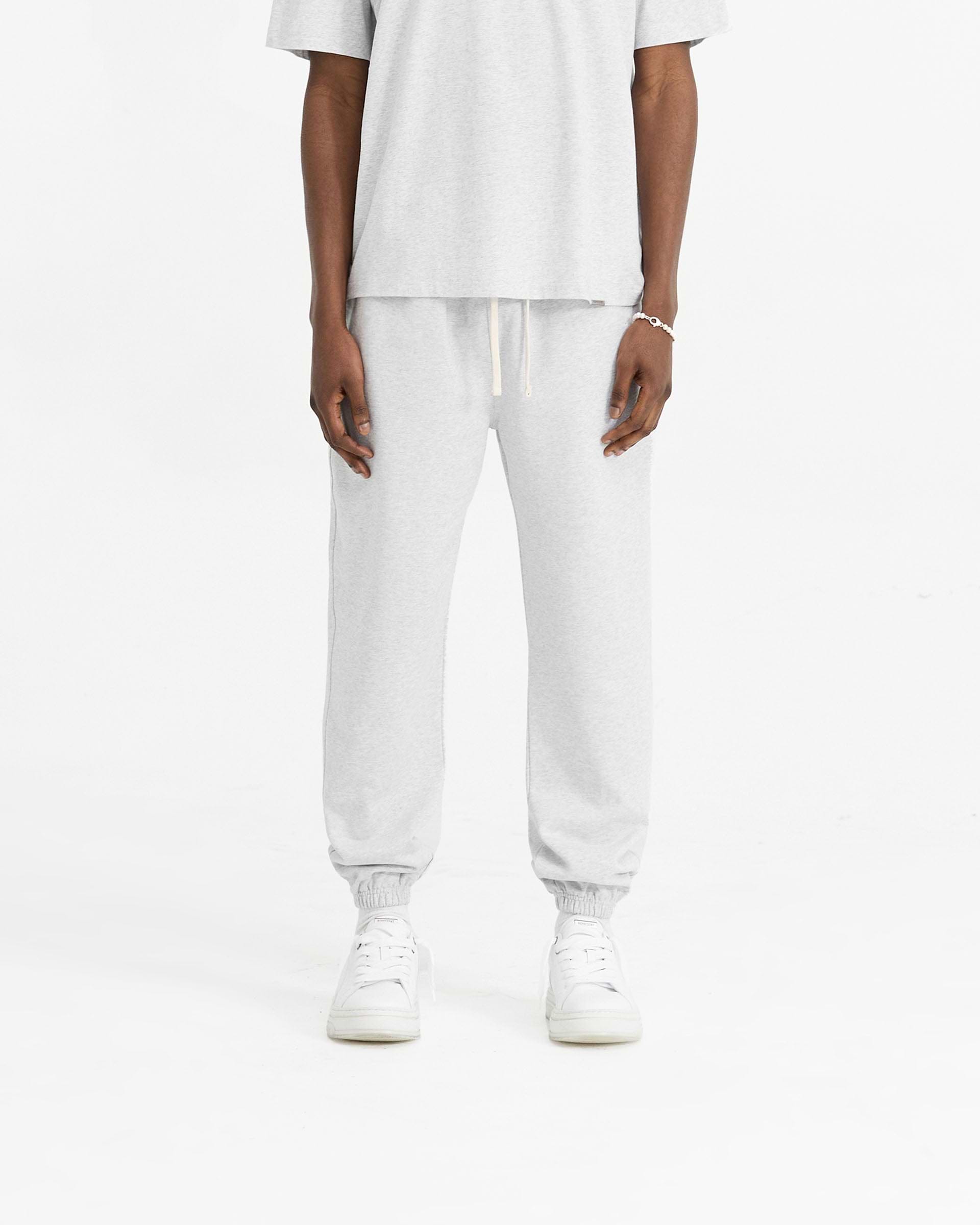Man wearing grey sweatpants on a plain white background | Initial Cuffed Sweatpant in Ice Grey Marl | Sweatpants with elasticated waistband and cuffed hems | Initial Pants | Represent Clo