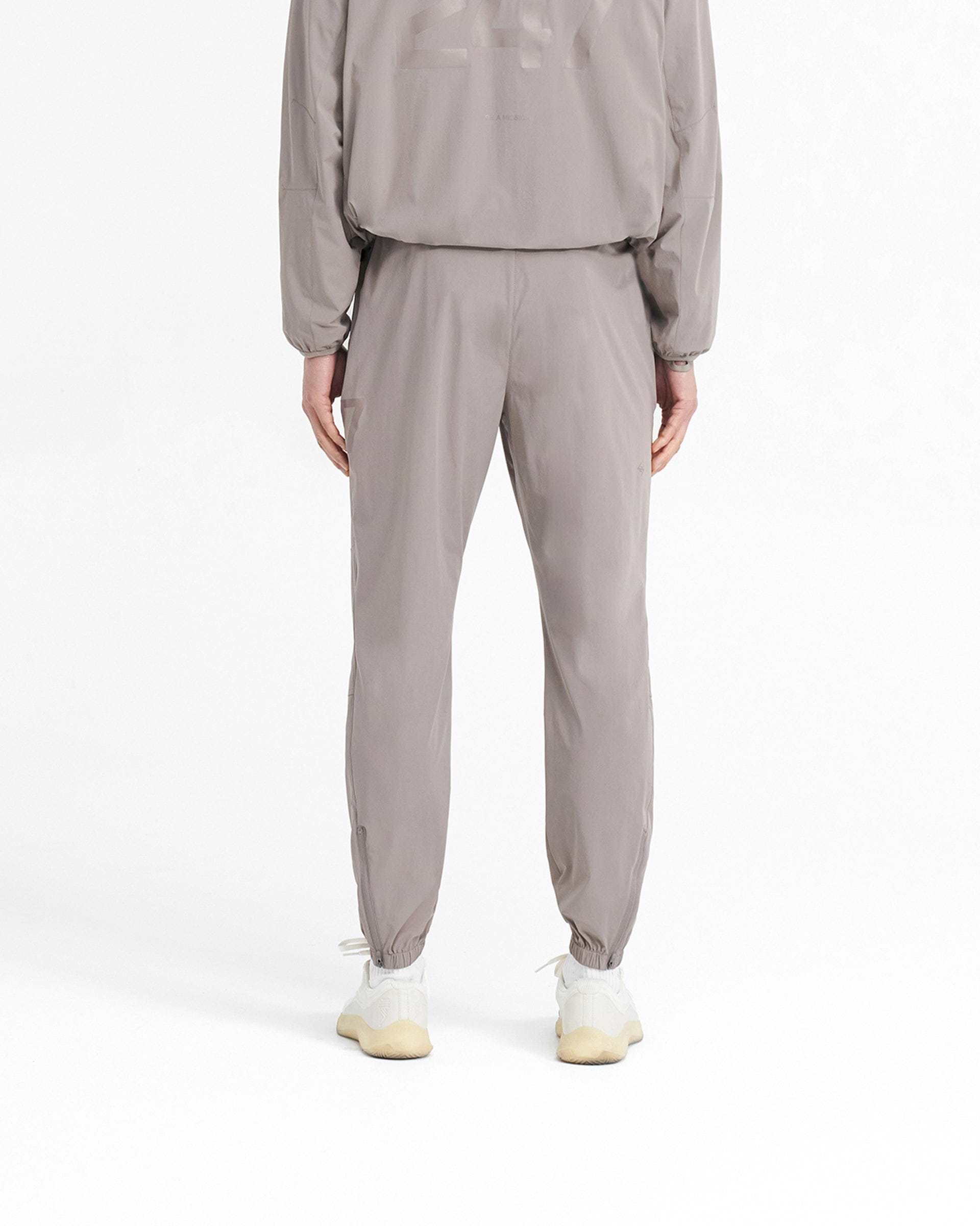Man wearing grey training pants on a plain white background | 247 Training Pant in Cinder | Training pants with elasticated waistband and zip pockets | 247 Pants | Represent Clo