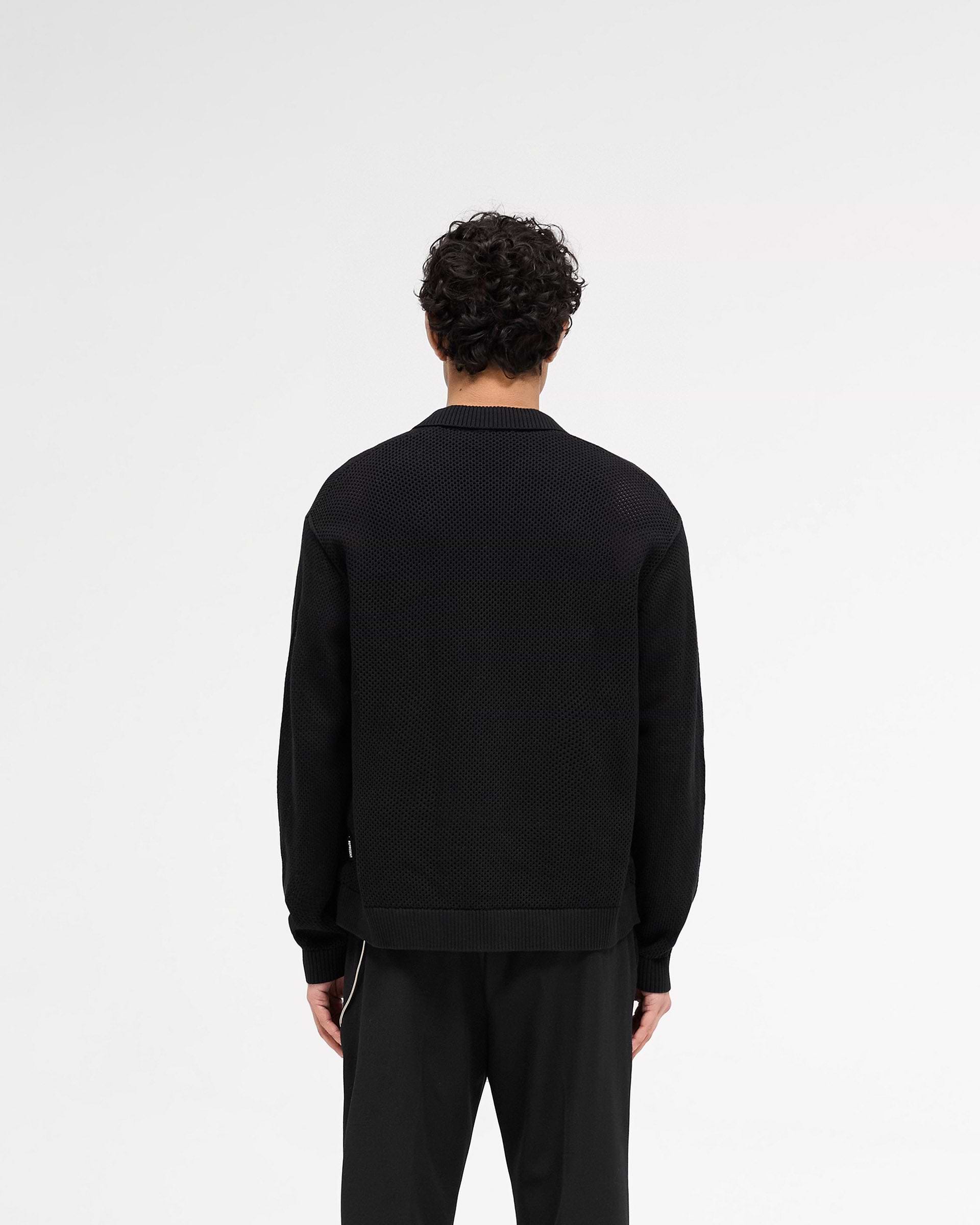 Man wearing a black mesh knit long sleeve shirt on a plain white background | Long Sleeve Mesh Knit Shirt in Jet Black | Perforated oversized knitwear | SS25 Knitwear | Represent Clo