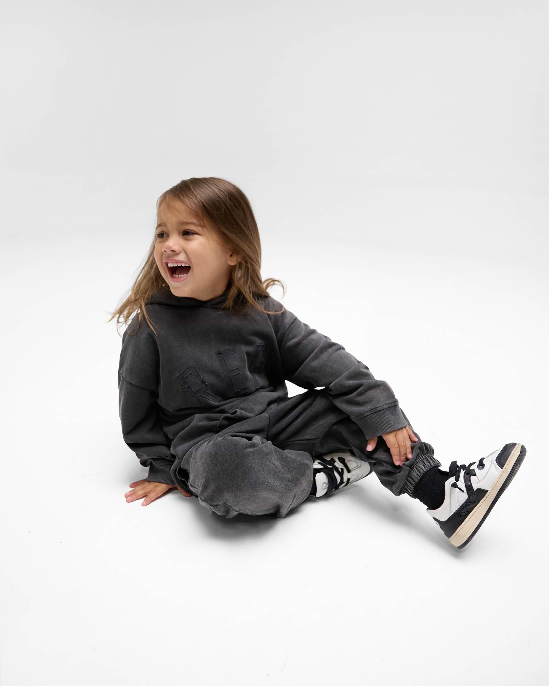 Back product image of kids black sweatpants on a plain white background | Mini Rep Applique Sweatpants in Vintage Black | Sweatpants with elasticated waistband and cuffs | FW24 Pants | Represent Clo