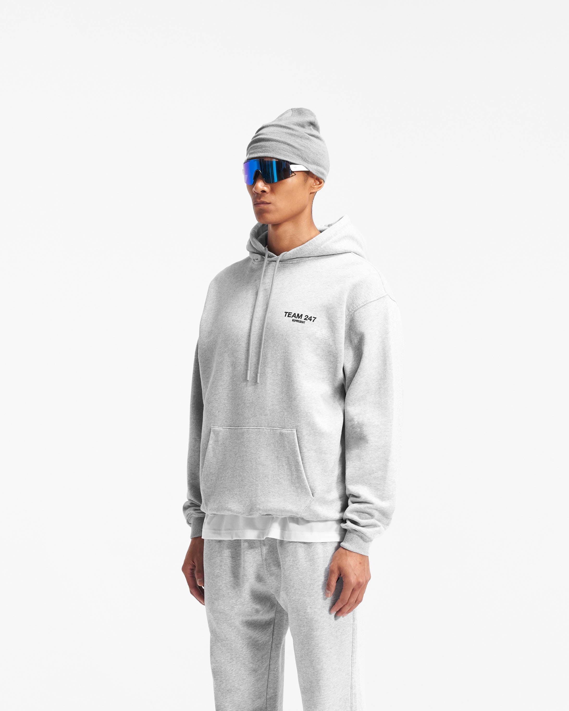 Man wearing an oversized grey hoodie on a plain white background | Team 247 Oversized Hoodie in Ash Grey | Training hoodie with ribbed cuffs and hem | 247 Hoodies | Represent Clo