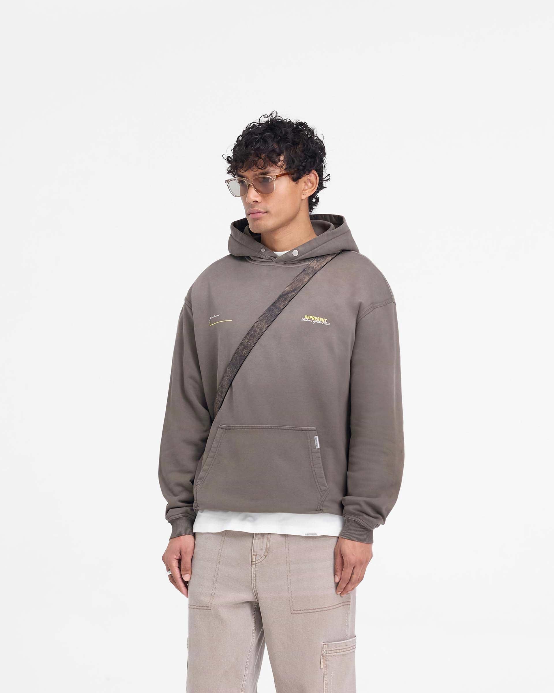Man wearing an oversized olive hoodie on a plain white background | Patron Of The Club Hoodie in Washed Olive | Heavy weight cotton hoodie with ribbed hem and cuffs | Patrons Hoodies | Represent Clo