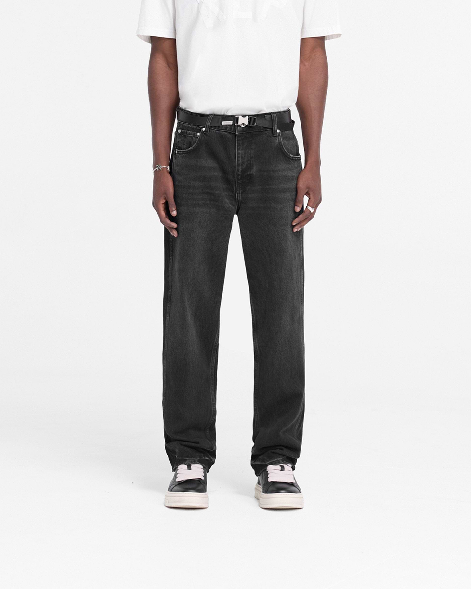 Man wearing black straight leg denim jeans on a plain white background | R2 Straight Leg Denim in Black | Straight leg jeans with embroidered initial | FW24 Denim | Represent Clo