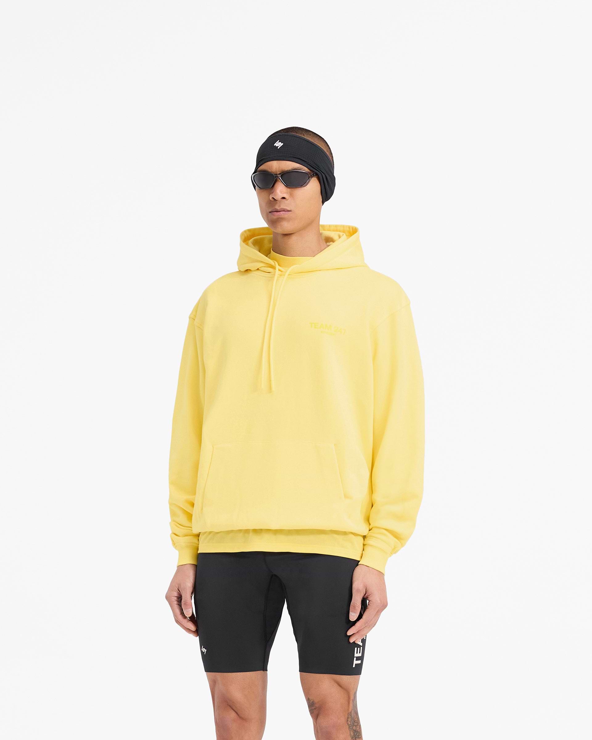Man wearing an oversized yellow hoodie on a plain white background | Team 247 Oversized Hoodie in Lemon | Oversized fit with ribbed cuffs and hem | 247 Hoodies | Represent Clo