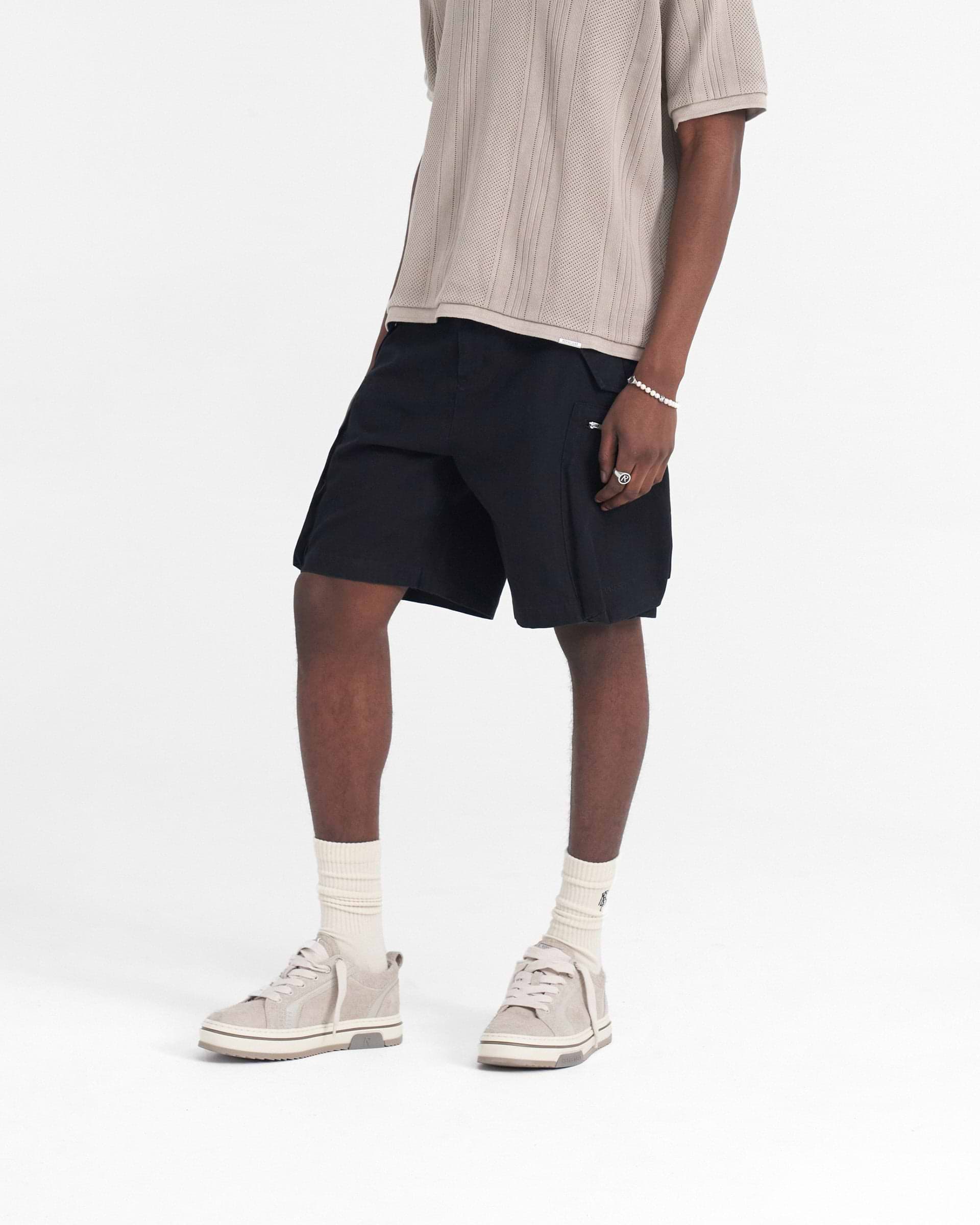 Man wearing baggy black shorts on a plain white background | Workshop Short in Black | Shorts with 3D back and cargo pockets | SS24 Shorts | Represent Clo