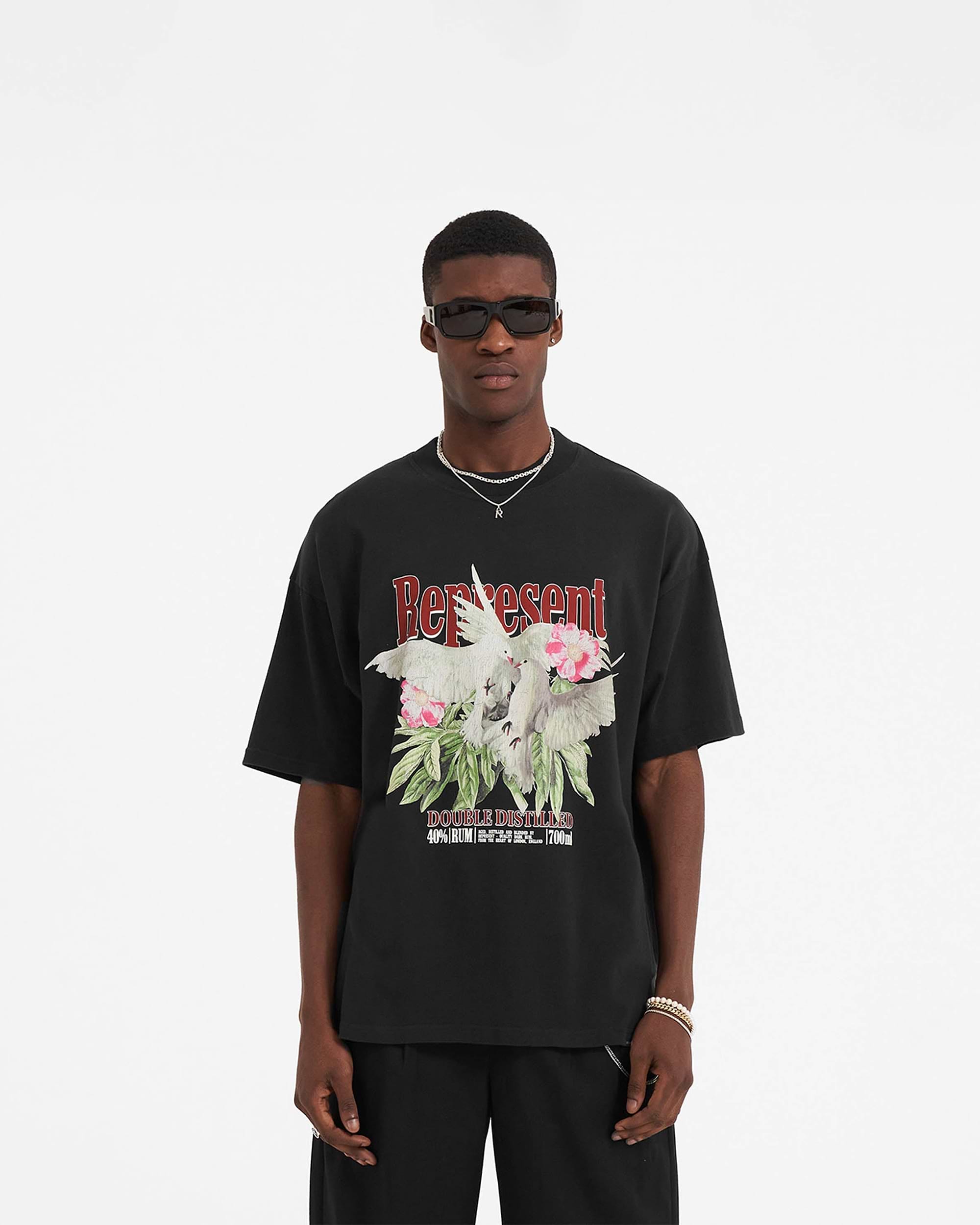 Man wearing a black t-shirt on a plain white background | Double Distilled T-Shirt in Off Black | Oversized black t-shirt with ribbed crewneck and graphic print | SS23 T-Shirts | Represent Clo