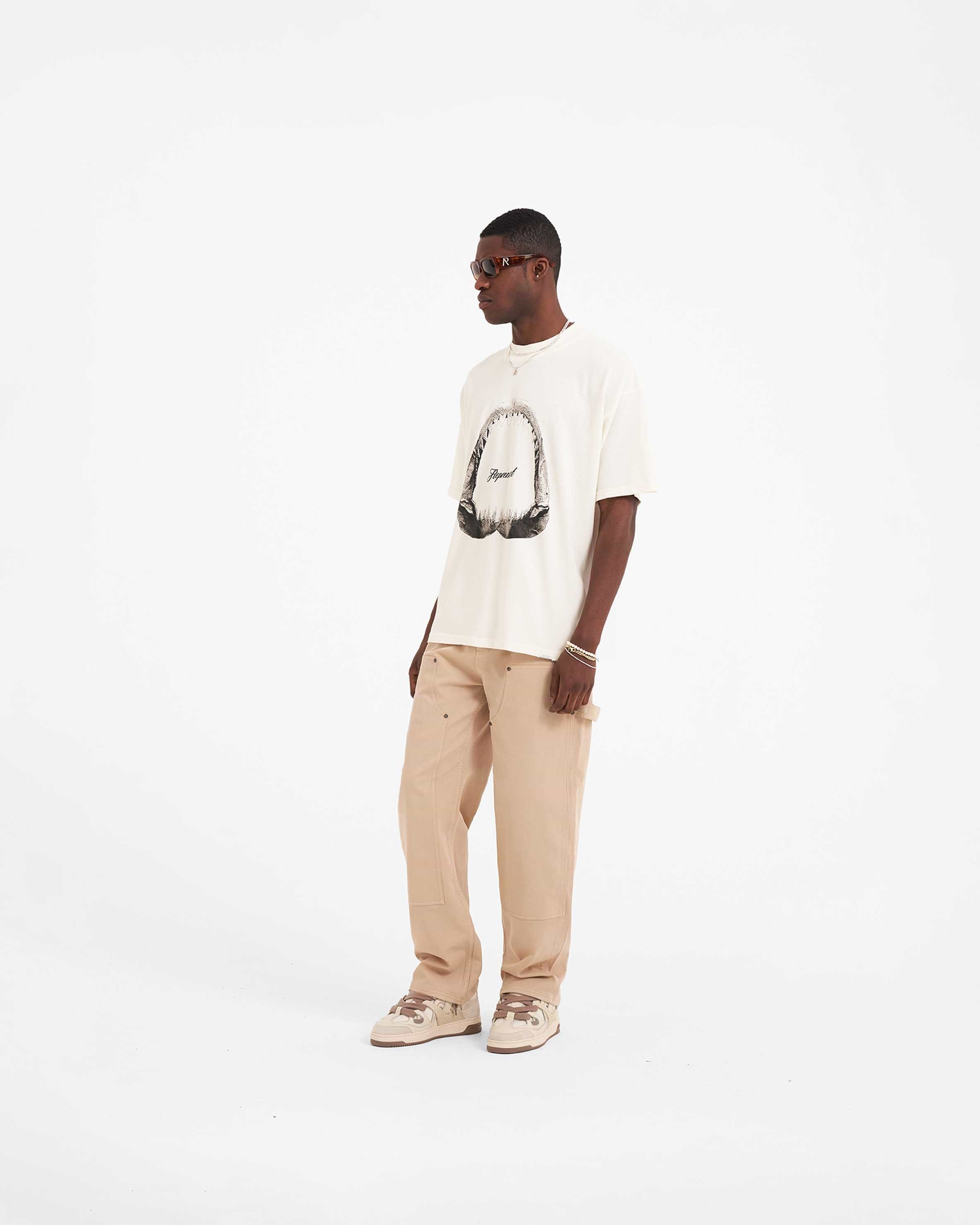 Man wearing a graphic t-shirt in white on a plain white background | Shark Jaws T-Shirt in Flat White | Oversized fit t-shirt with Shark Jaws graphic | SS23 T-Shirts | Represent Clo