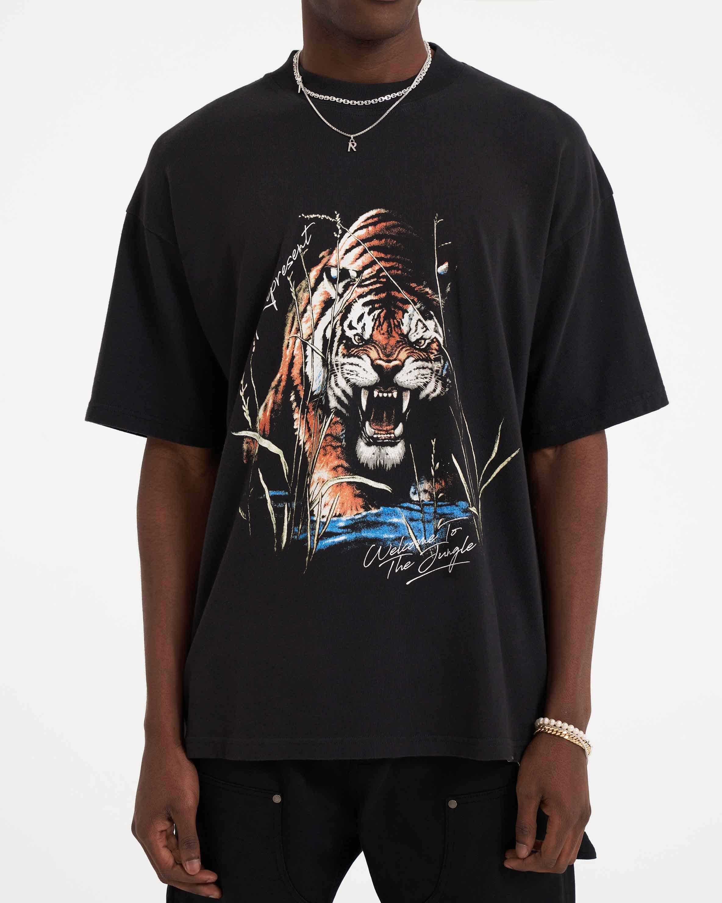 Man wearing an oversized black graphic t-shirt on a plain white background | Welcome To The Jungle T-Shirt in Off Black | Graphic t-shirt with ribbed crewneck | SS23 T-Shirts | Represent Clo