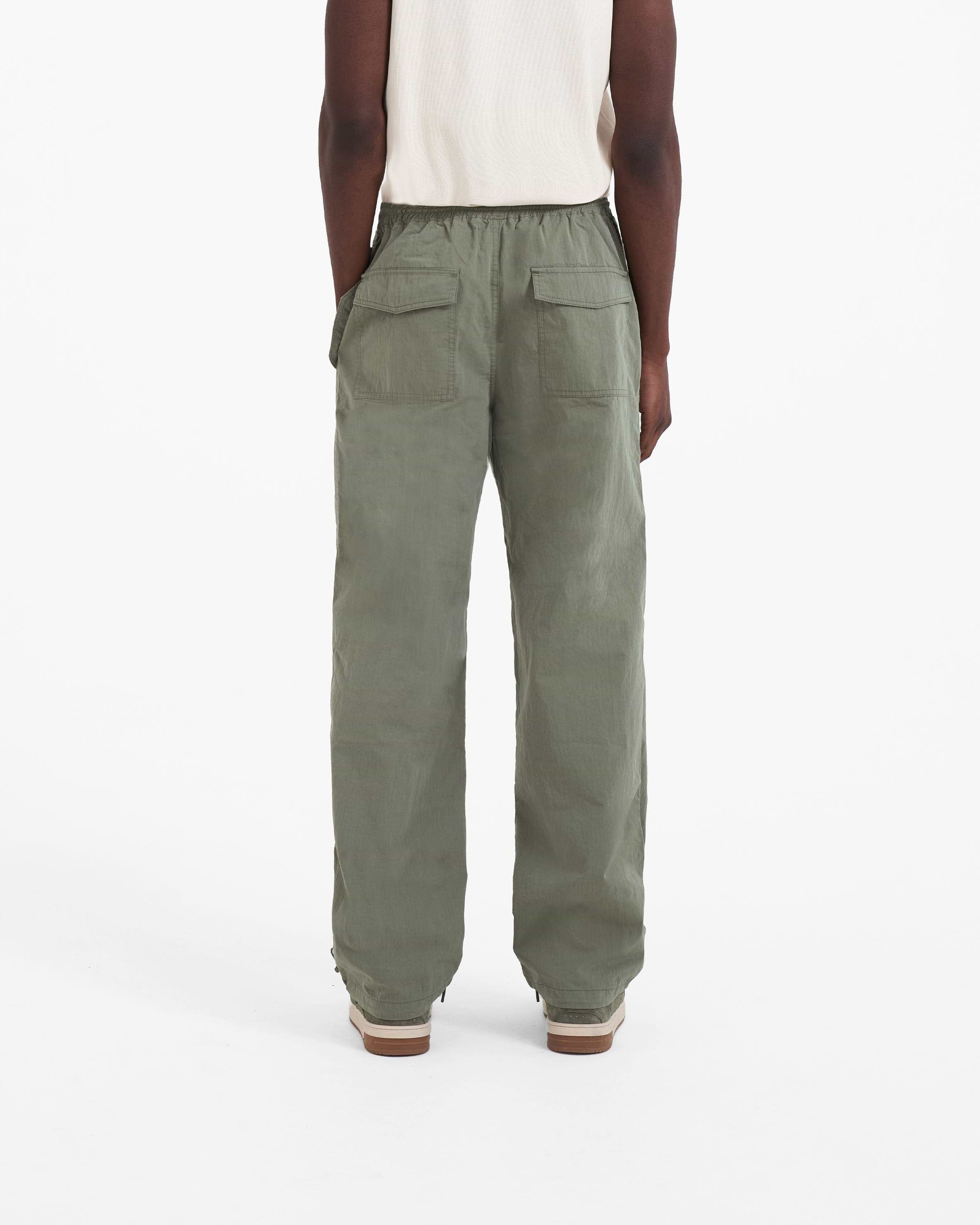 Man wearing khaki pants on a plain white background | Parachute Pant in Khaki | Baggy fit pants with elasticated waistband and drawstring | SC23 Pants | Represent Clo