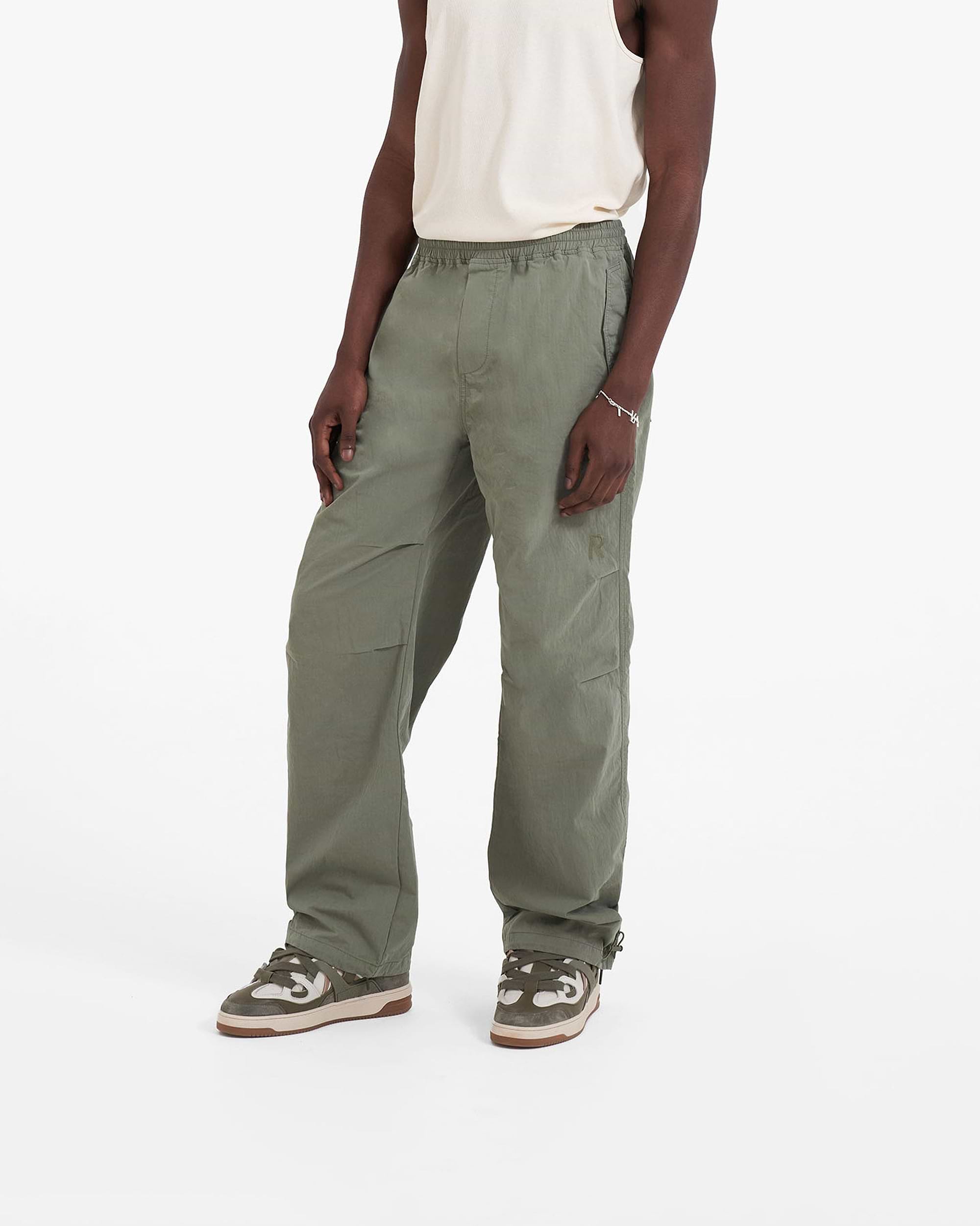 Man wearing khaki pants on a plain white background | Parachute Pant in Khaki | Baggy fit pants with elasticated waistband and drawstring | SC23 Pants | Represent Clo