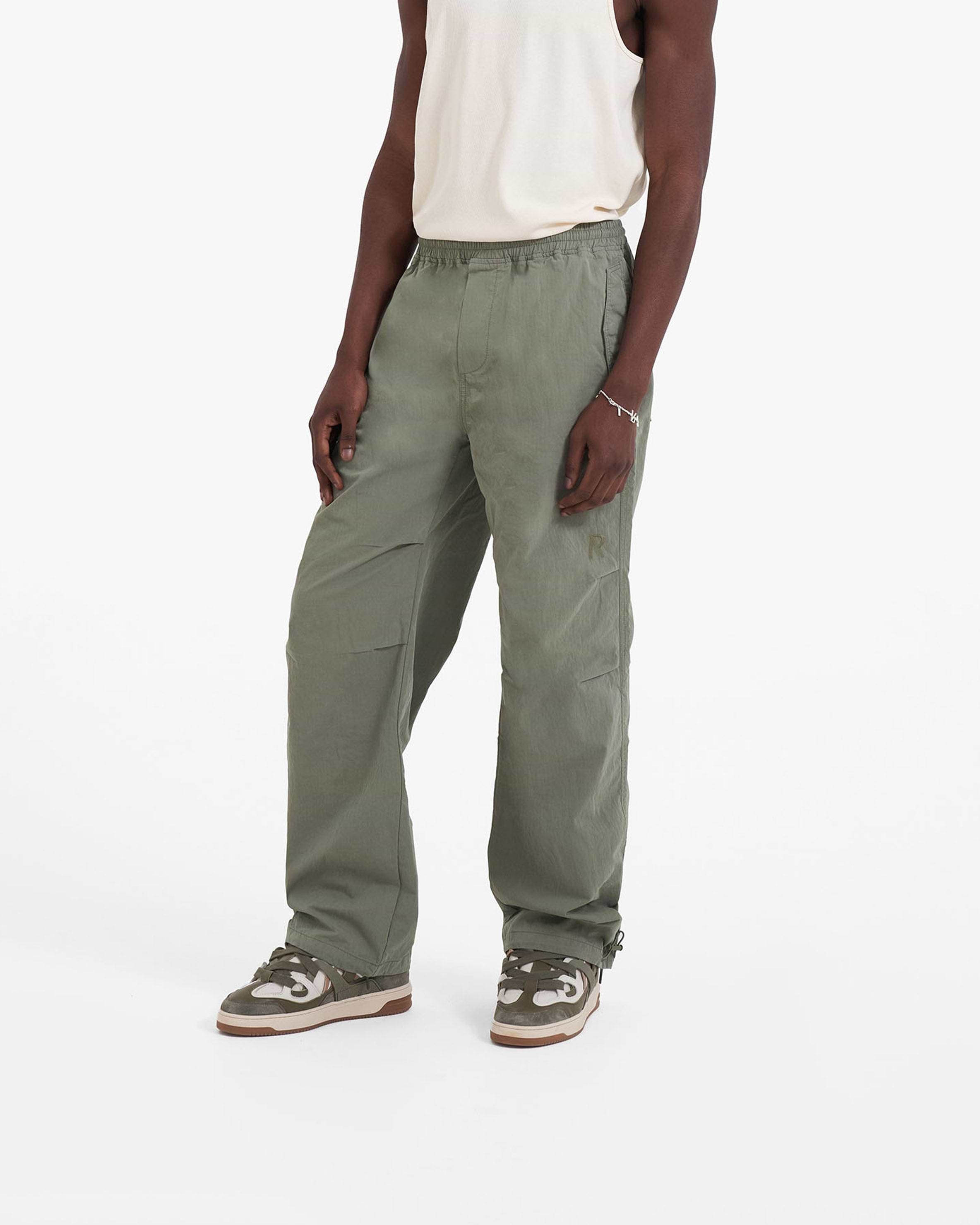 Man wearing khaki pants on a plain white background | Parachute Pant in Khaki | Baggy fit pants with elasticated waistband and drawstring | SC23 Pants | Represent Clo